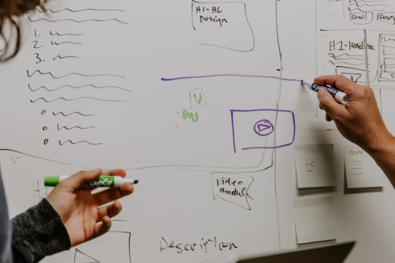 Two collaborators planning ideas on a studio whiteboard